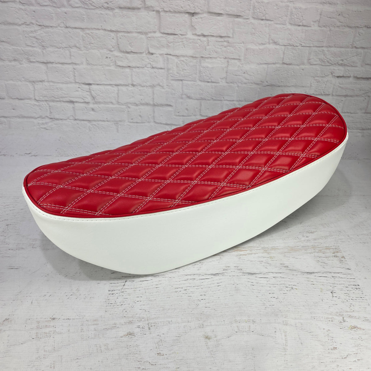 Low side view of a red diamond stitch Honda DAX 125 seat cover with white stitching and contrasting white sides, handmade by Cheeky Seats