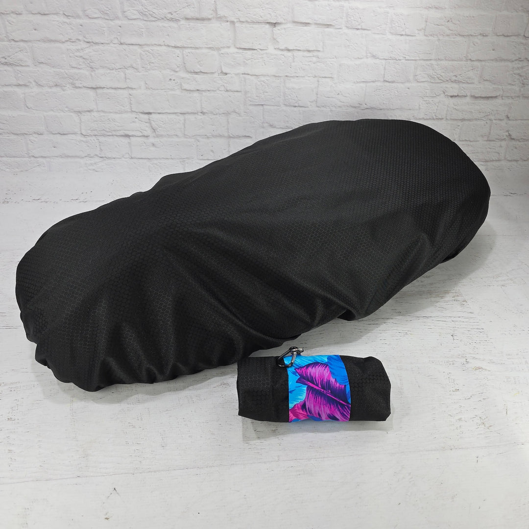 Black honeycomb Honda DAX 125 protective seat cover with a rolled pouch, blue leaf strap and clip, by Cheeky Seats