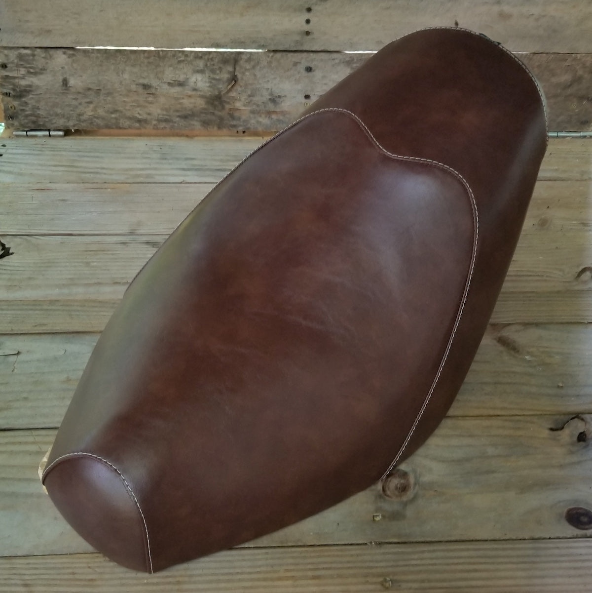 Distressed whiskey-brown Cheeky Seats cover on a Genuine Buddy low-profile seat, overhead studio view