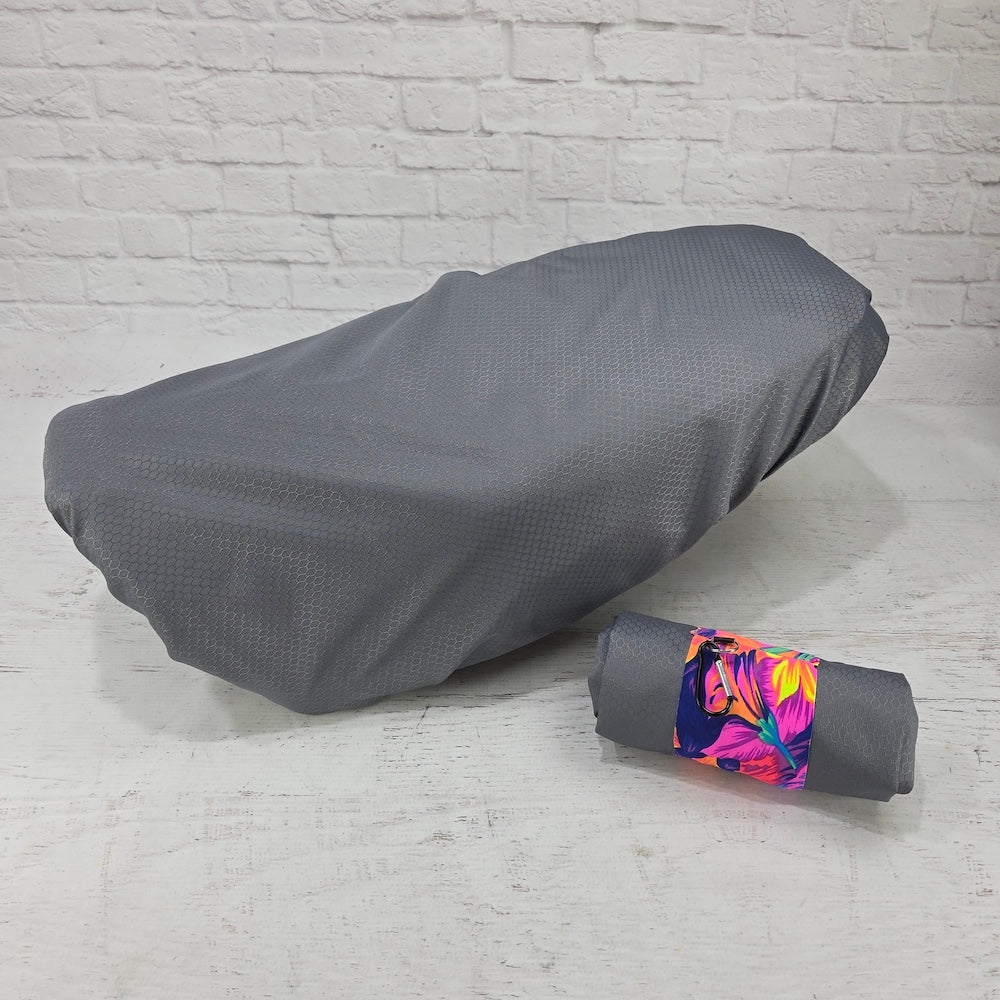 Pewter Honda DAX 125 protective seat cover with a rolled carry pouch and bright floral strap, by Cheeky Seats