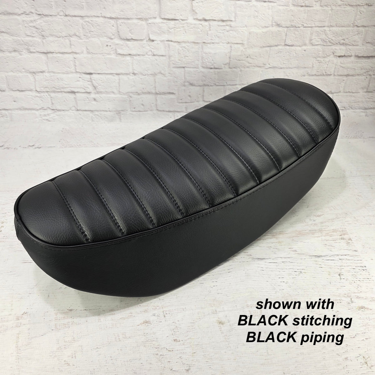 Black tuck-and-roll Honda DAX 125 seat cover with subtle black stitching and black piping, handmade by Cheeky Seats