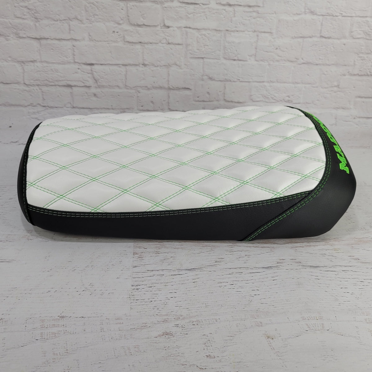 White diamond-stitched Maddog seat cover with green contrast stitching, black side panels, and green embroidery, handmade by Cheeky Seats