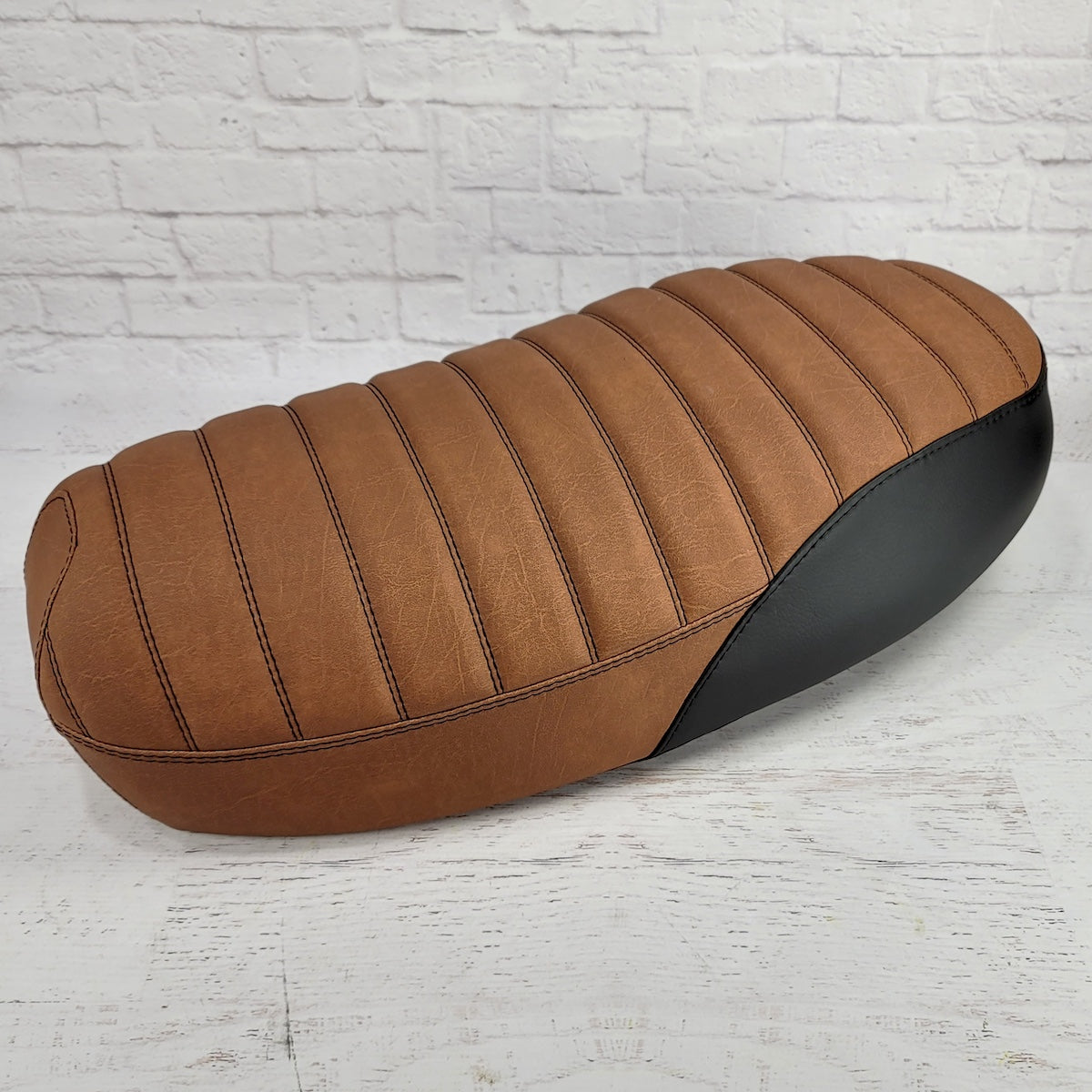 Rear three-quarter view of an anti-slip  distressed Slickrock brown Yamaha Zuma II BWS 49/50 Prebug seat cover with tuck-and-roll stitching and black side panels, handmade by Cheeky Seats