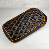 Black diamond-stitched Maddog seat cover with orange contrast stitching and orange piping, handmade by Cheeky Seats