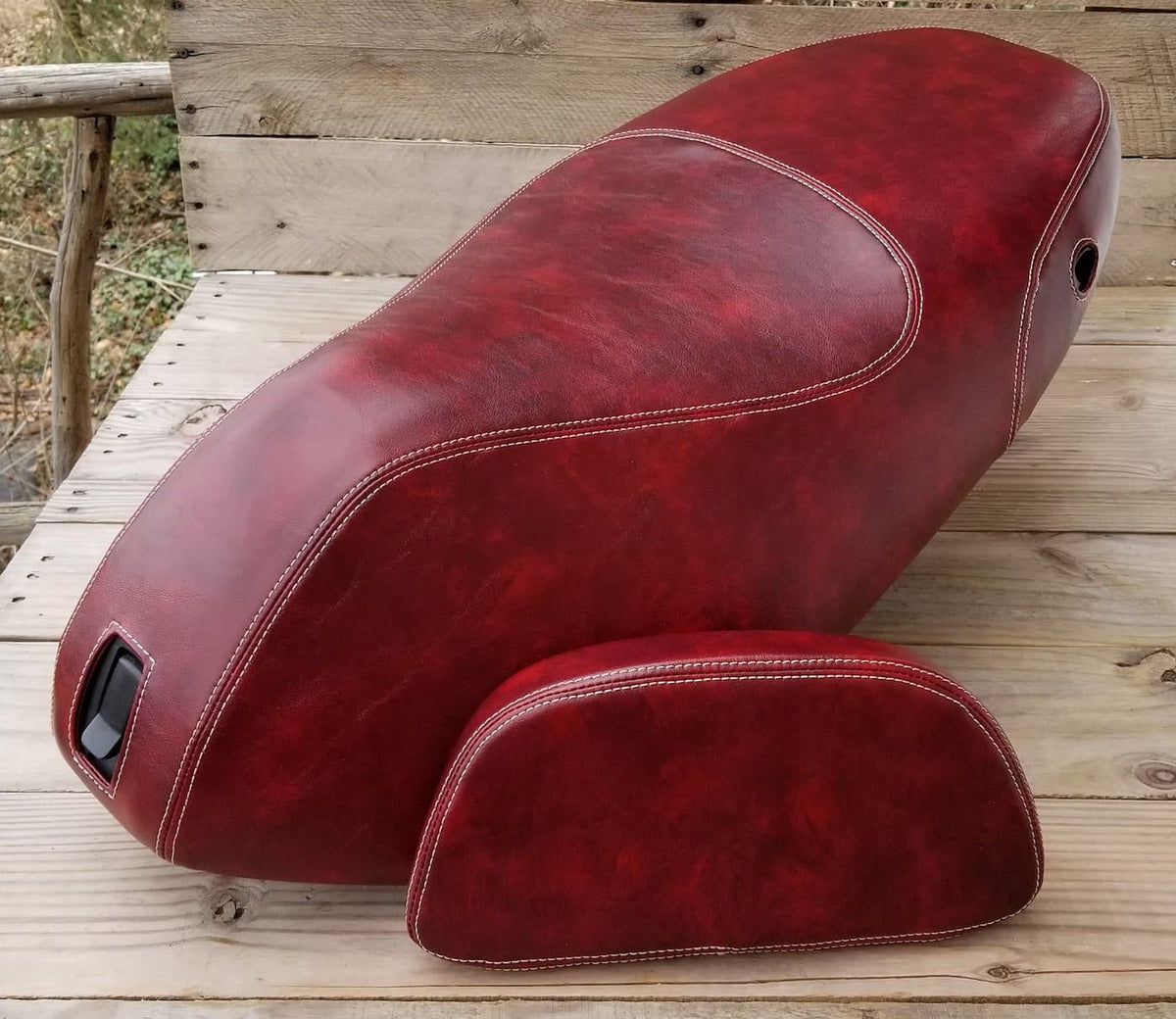 Oxblood Piaggio Fly seat cover with cream French seams beside its matching upholstered top-case pad, handmade by Cheeky Seats